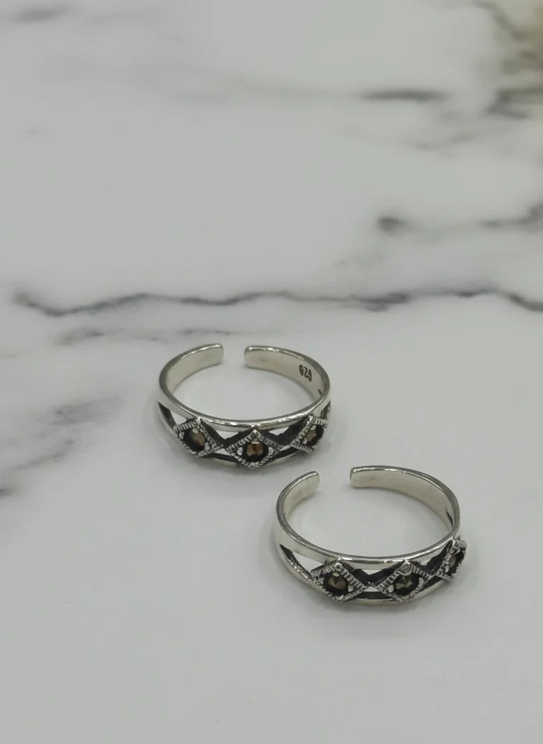 Two silver rings with decorative elements on a marble surface