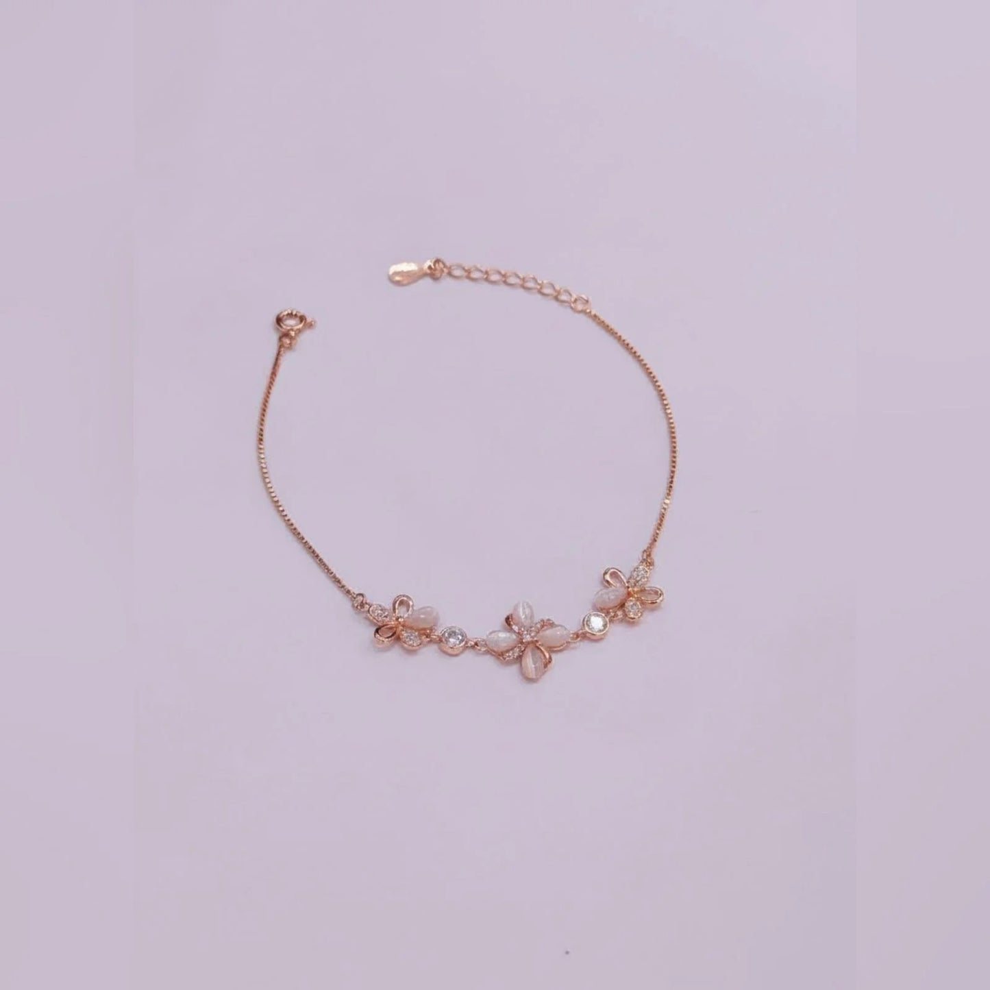Rose gold bracelet with floral designs on a light purple background