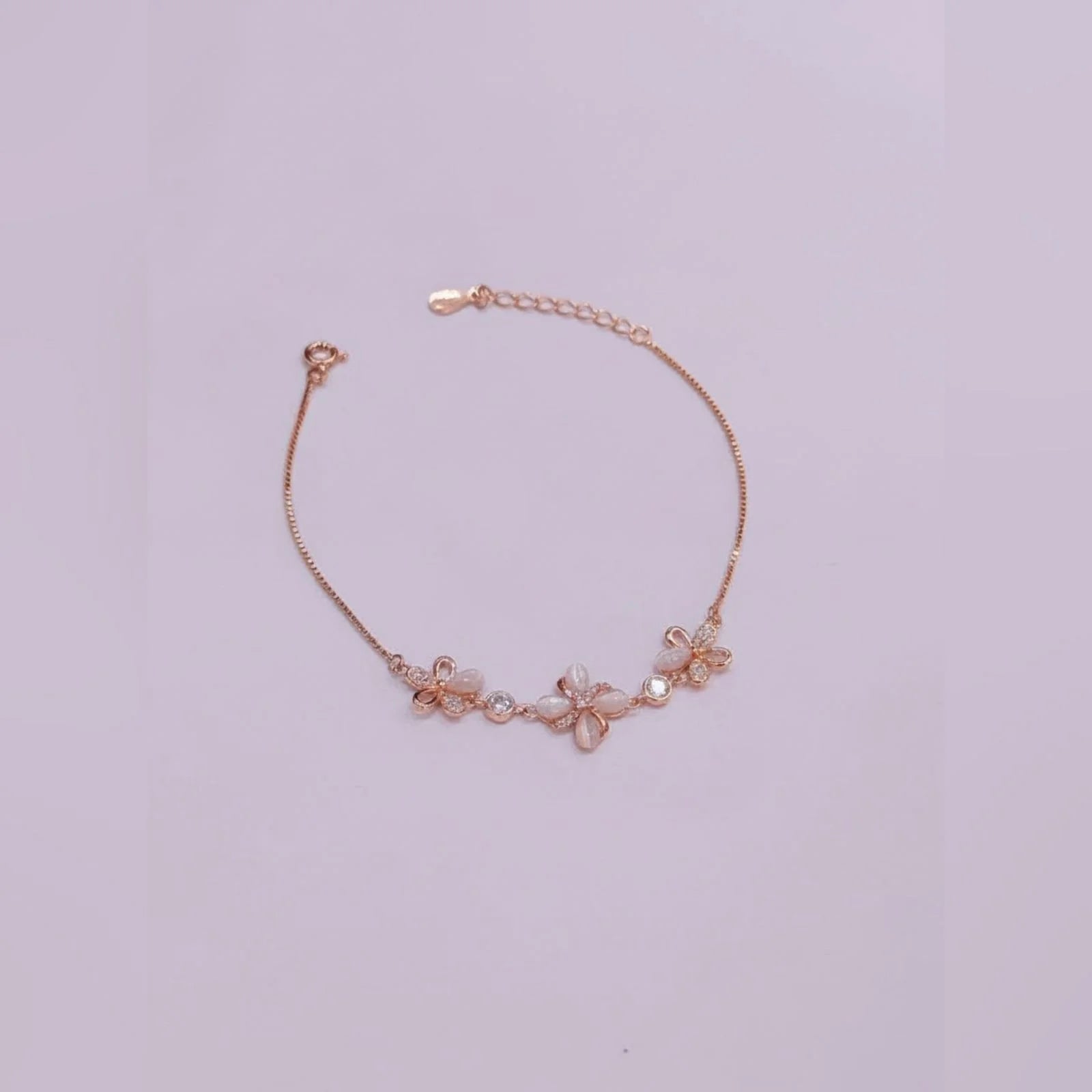 Rose gold bracelet with floral designs on a light purple background