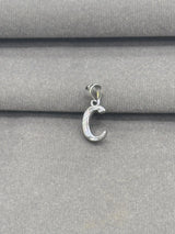 Silver C pendant on a gray fabric background