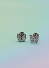 Butterfly-shaped earrings with gemstones on a gradient background