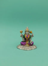 Small figurine of a deity with colorful attire on a green background