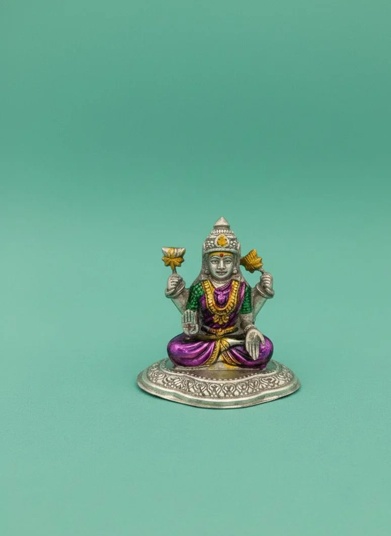 Small figurine of a deity with colorful attire on a green background