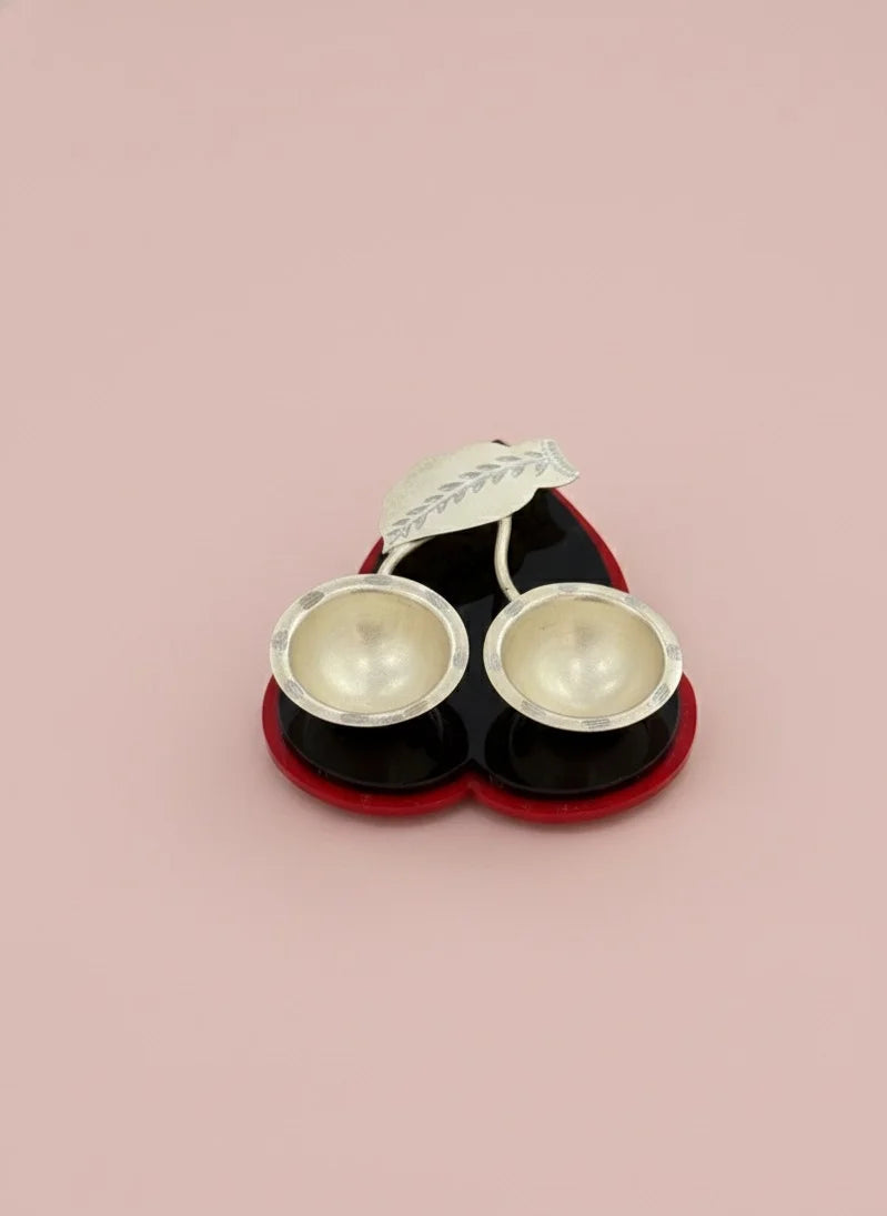 Pair of silver earrings in a black and red box on a pink background