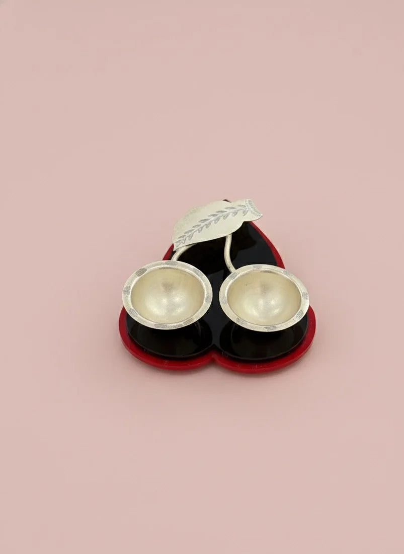 Pair of silver earrings in a black and red box on a pink background
