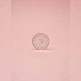 Silver coin with a symbol on a pink background