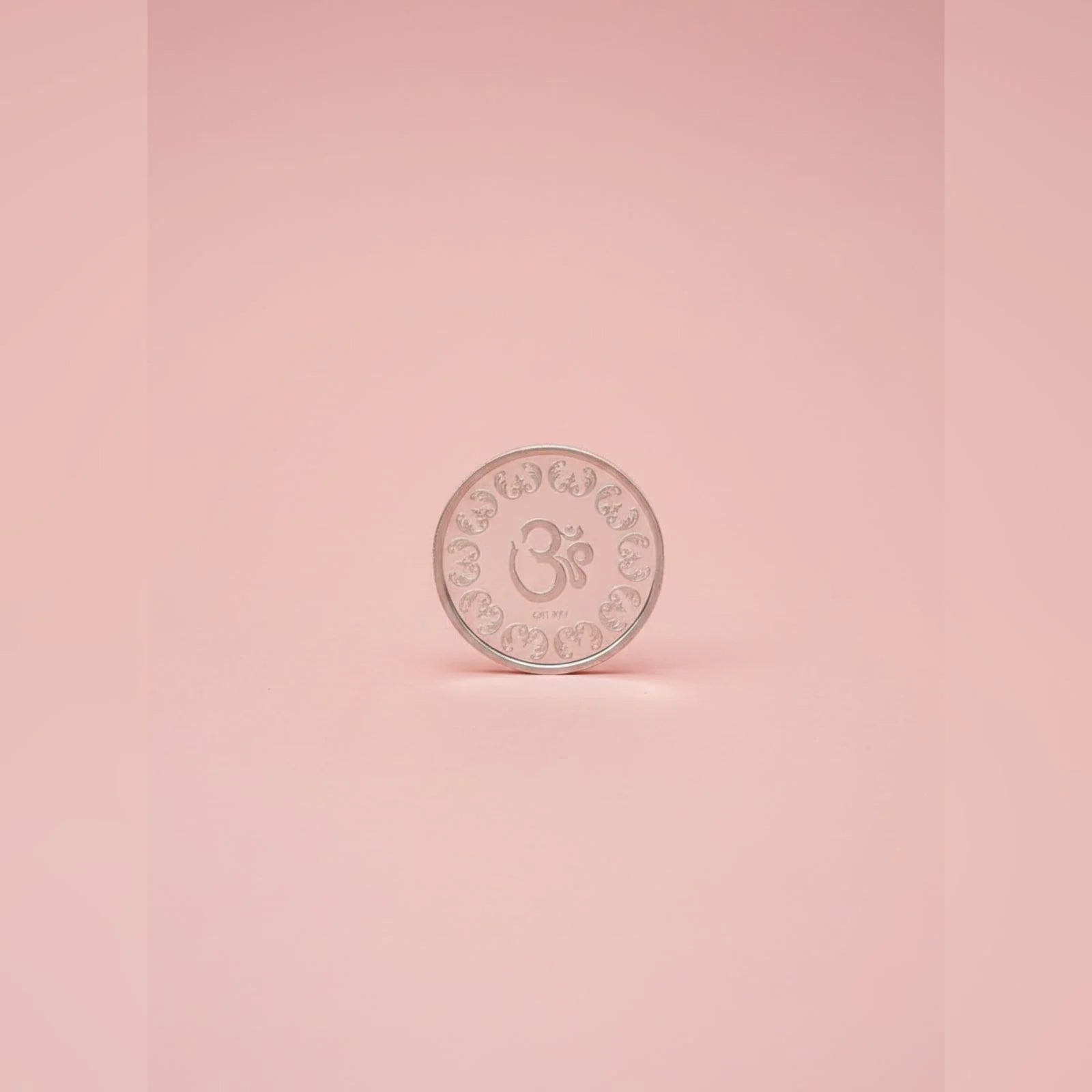 Silver coin with a symbol on a pink background