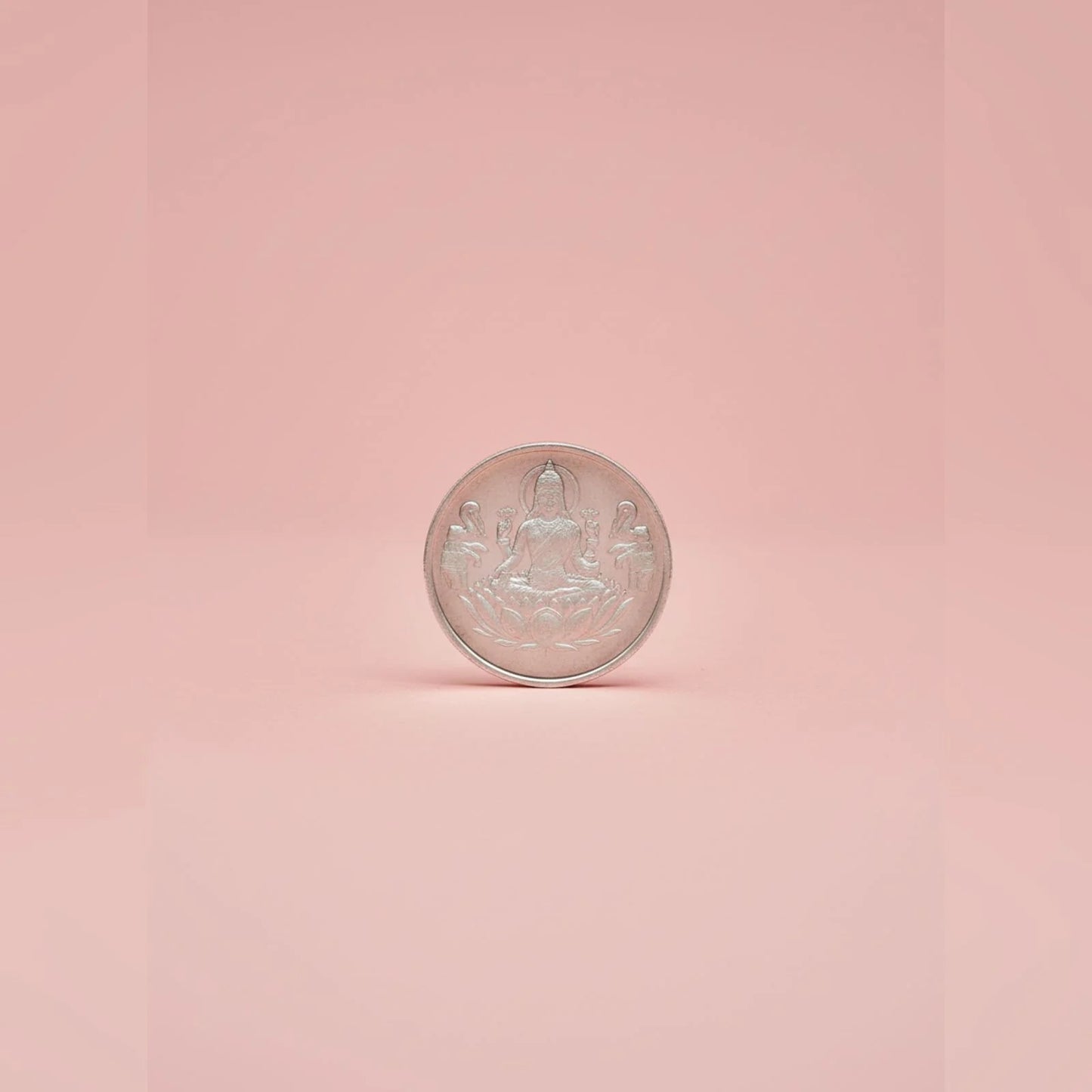 Silver coin with Lakshmifigure on a pink background
