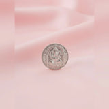 Silver coin with a deity figure on a pink and white gradient background