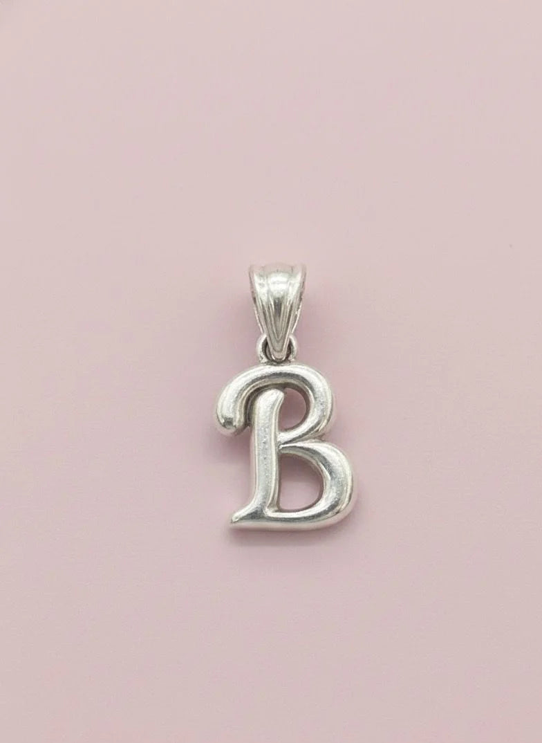 Silver 'B' pendant on a pink background