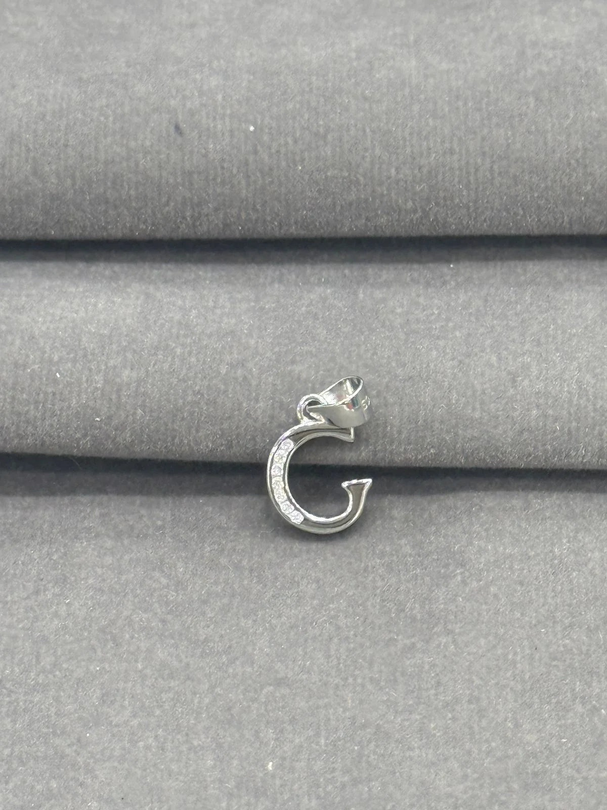 Silver pendant on a gray fabric background