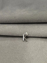 Silver letter 'K' charm on a gray fabric background