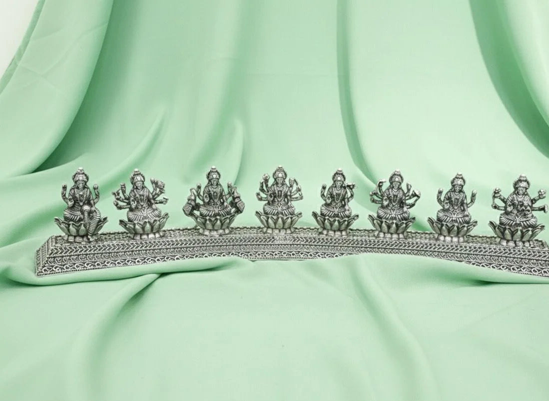 Decorative silver metal piece with figures on a light green fabric background