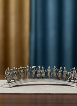 Silver figurine of people on a bridge with a blue and brown curtain background