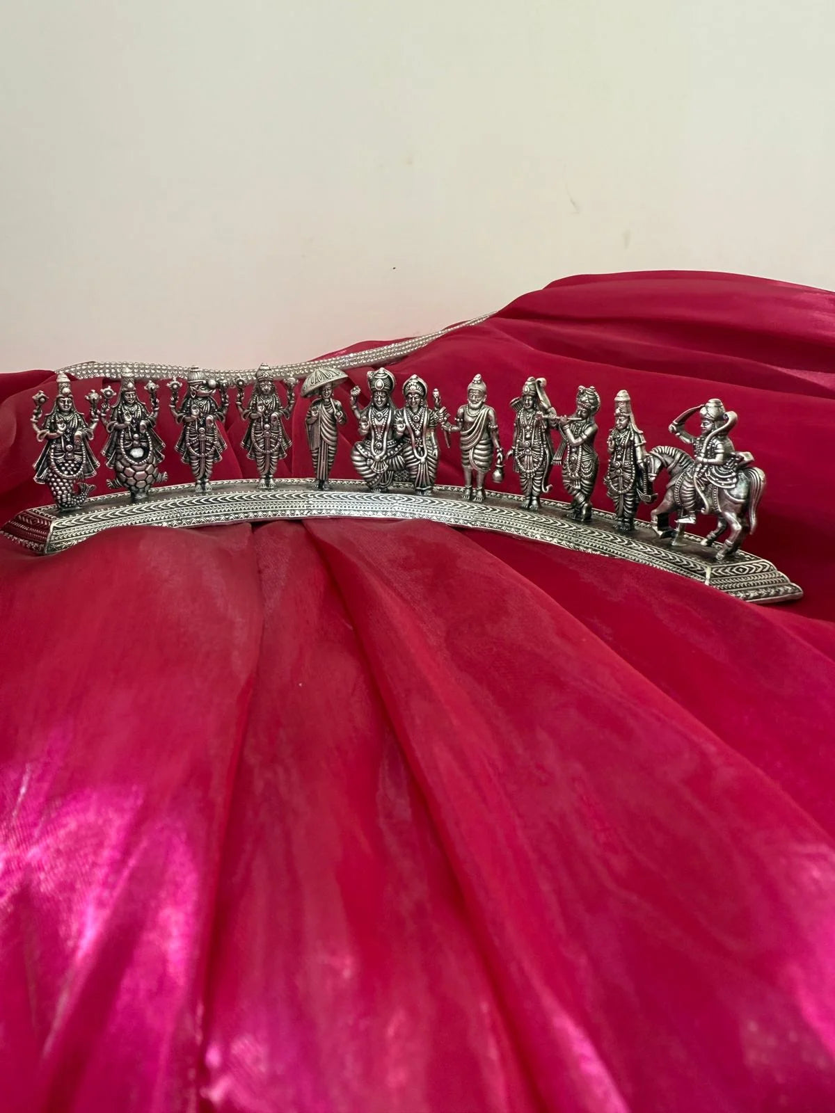 Decorative silver tiara with figures on a red fabric background