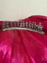 Decorative silver tiara with figures on a red fabric background