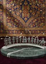 Silver diorama of figures on a marble base with a patterned rug in the background