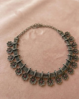 Decorative necklace with floral designs on a pink background