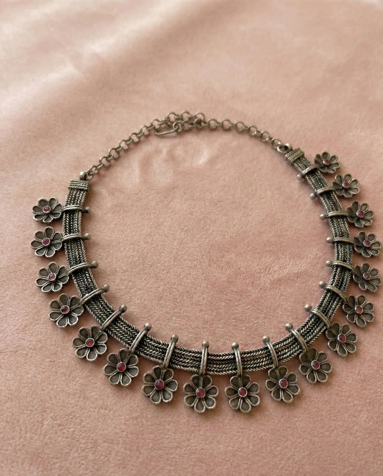 Decorative necklace with floral designs on a pink background