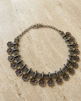 Silver floral necklace on a beige stone surface