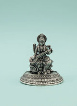 Silver statue of a musical instrument player on a light blue background
