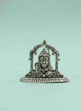 Decorative metal piece with a face design on a light green background