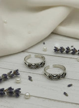 Two silver rings on a wooden surface with lavender and pearls.