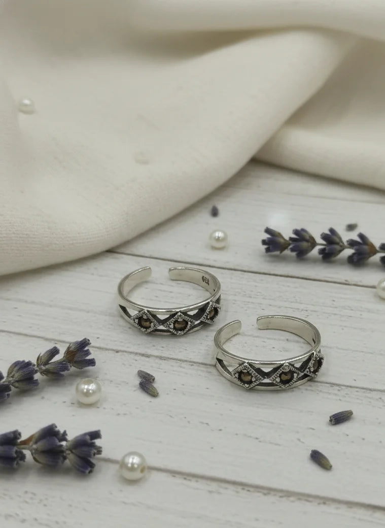 Two silver rings on a wooden surface with lavender and pearls.