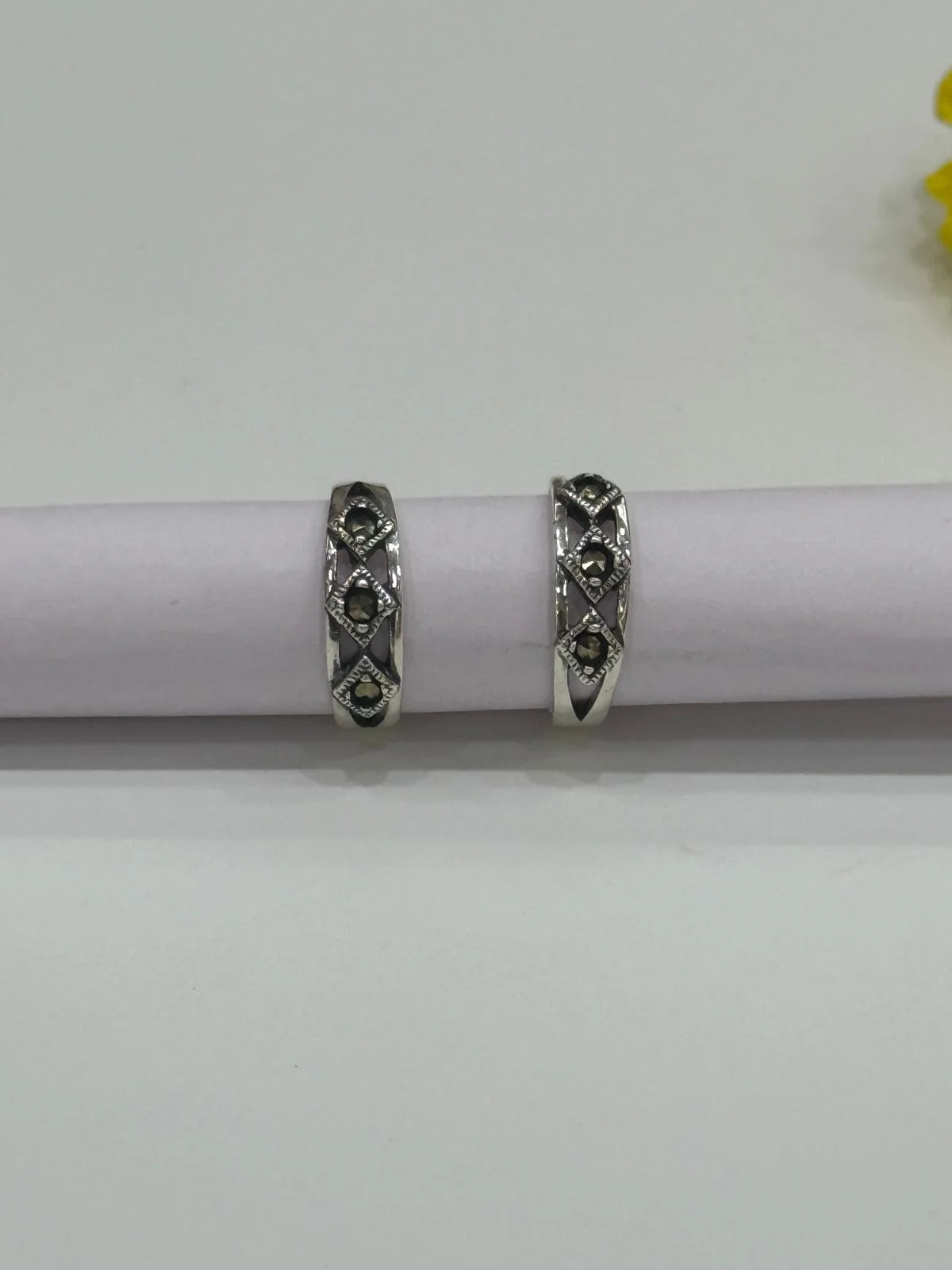 Pair of silver toe rings with gemstones on a white background