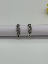 Pair of silver toe rings with gemstones on a white background