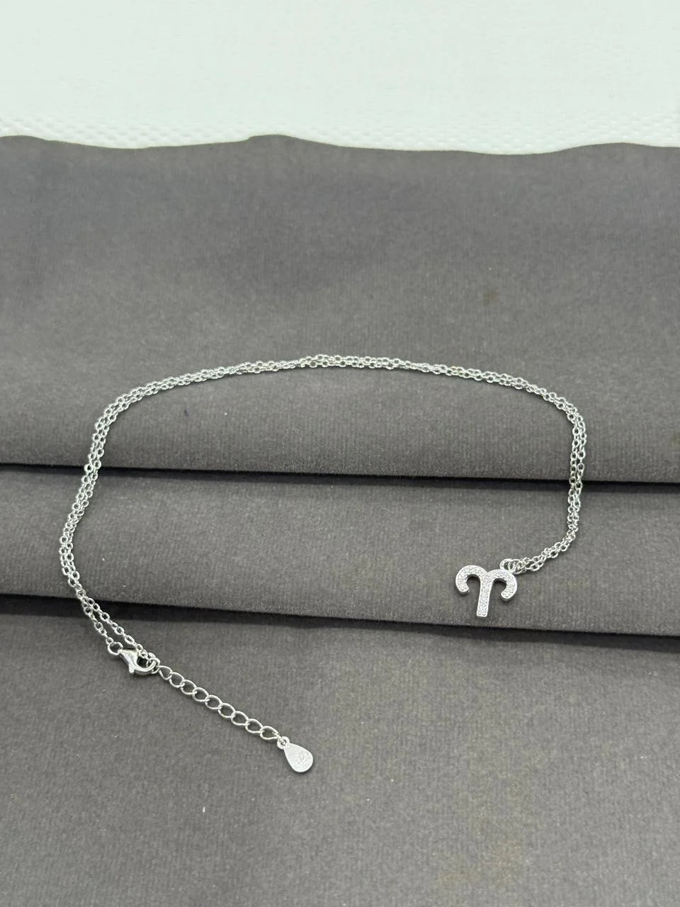 Silver necklace with a unique design on a gray surface