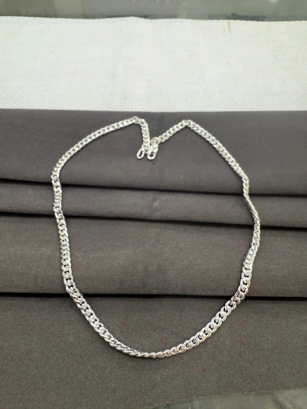 Silver chain necklace on a gray fabric background