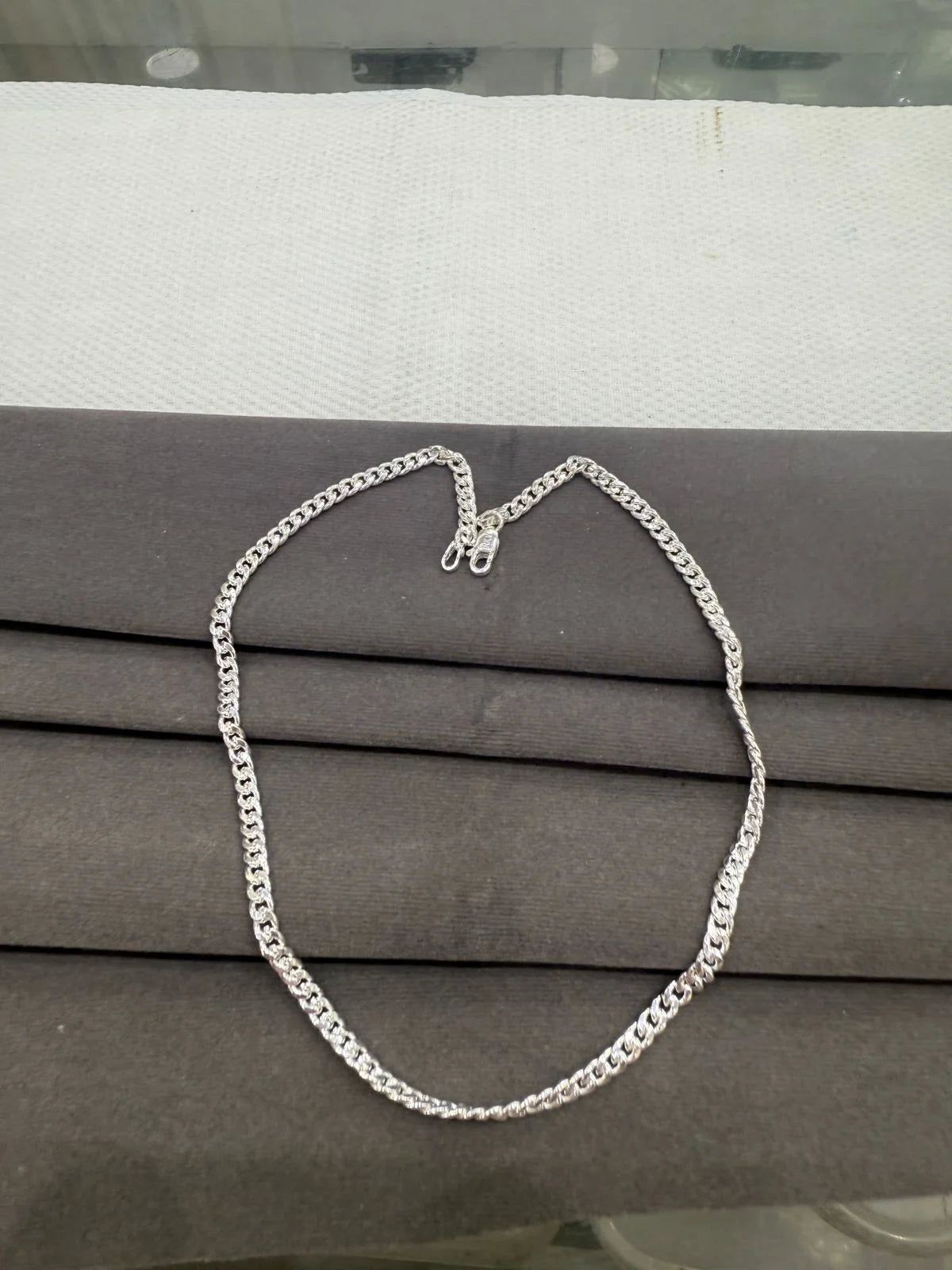 Silver chain necklace on a gray surface