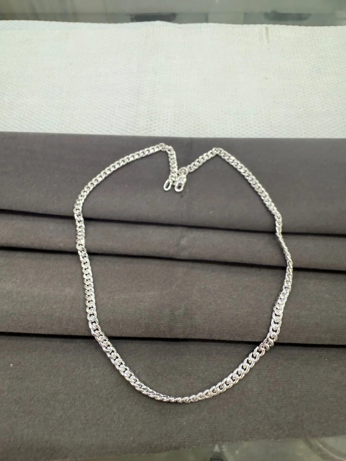 Silver chain necklace on a gray surface