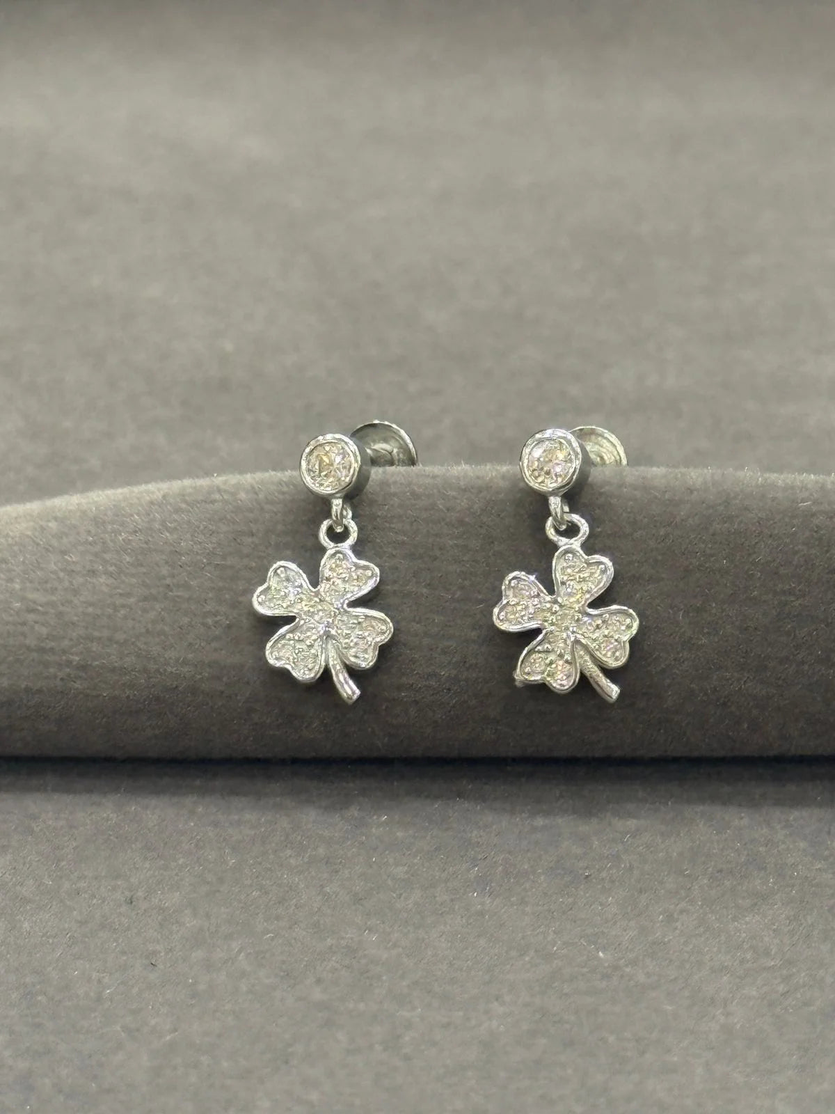 Silver shamrock earrings on a gray surface