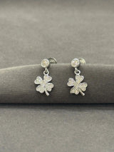 Silver shamrock earrings on a gray surface