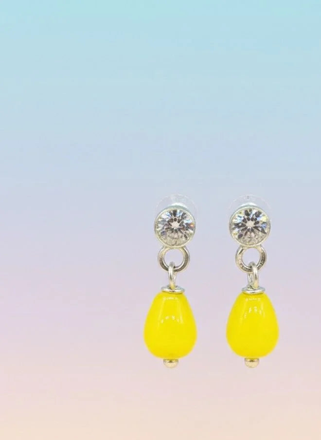 Yellow teardrop earrings with clear stones on a gradient background