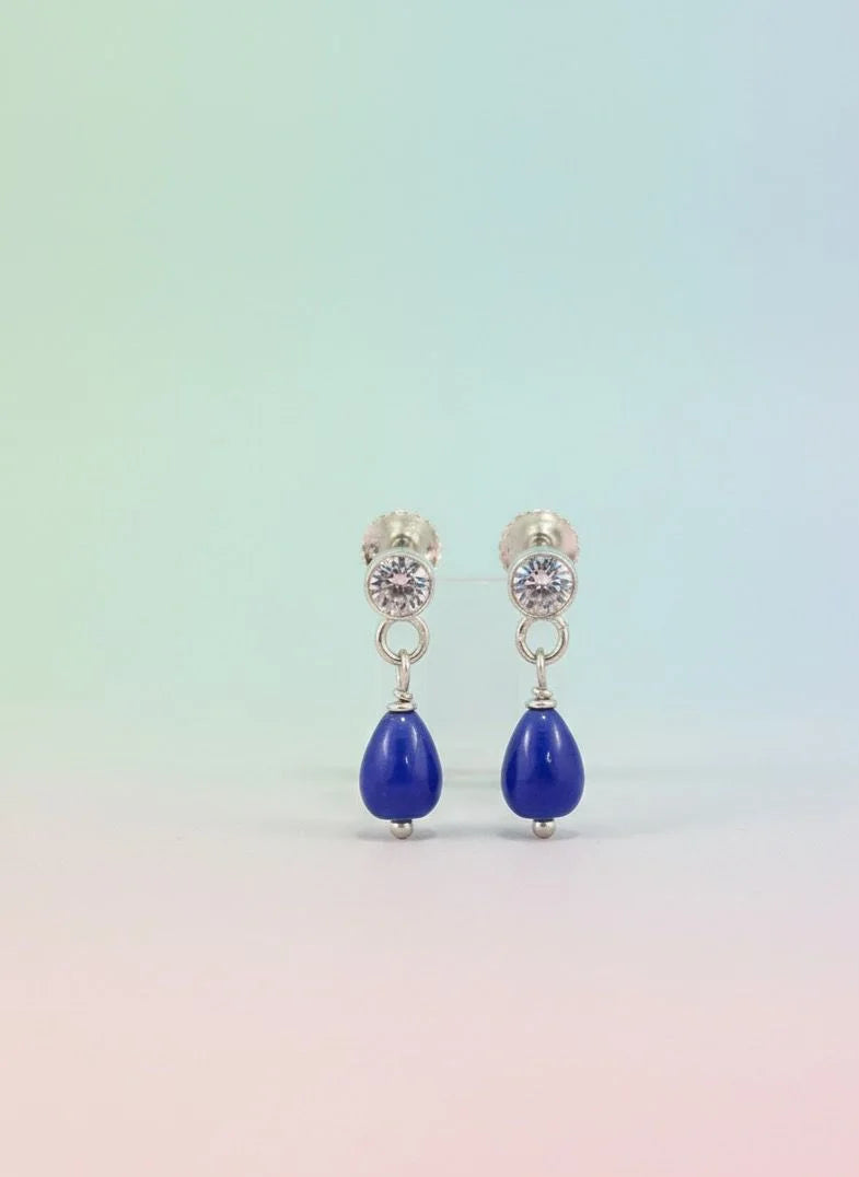 Pair of earrings with blue teardrop stones on a gradient background