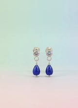 Pair of earrings with blue teardrop stones on a gradient background
