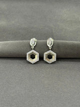 Hexagonal earrings with diamond-like stones on a gray surface