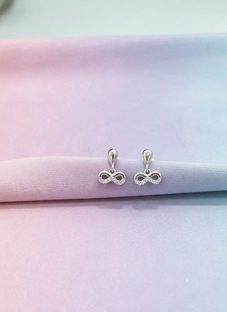 Silver infinity symbol earrings on a pastel gradient background