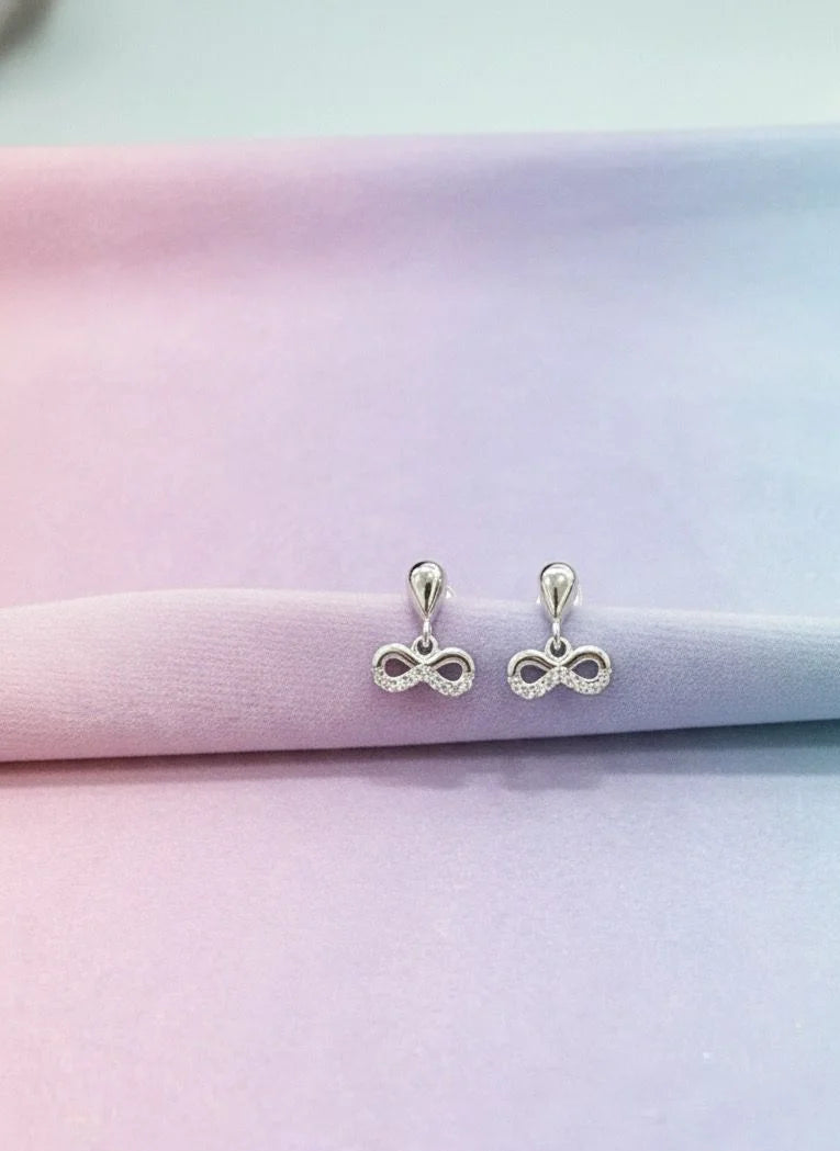 Silver infinity symbol earrings on a pastel gradient background