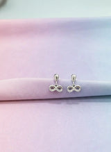Silver infinity symbol earrings on a pastel gradient background