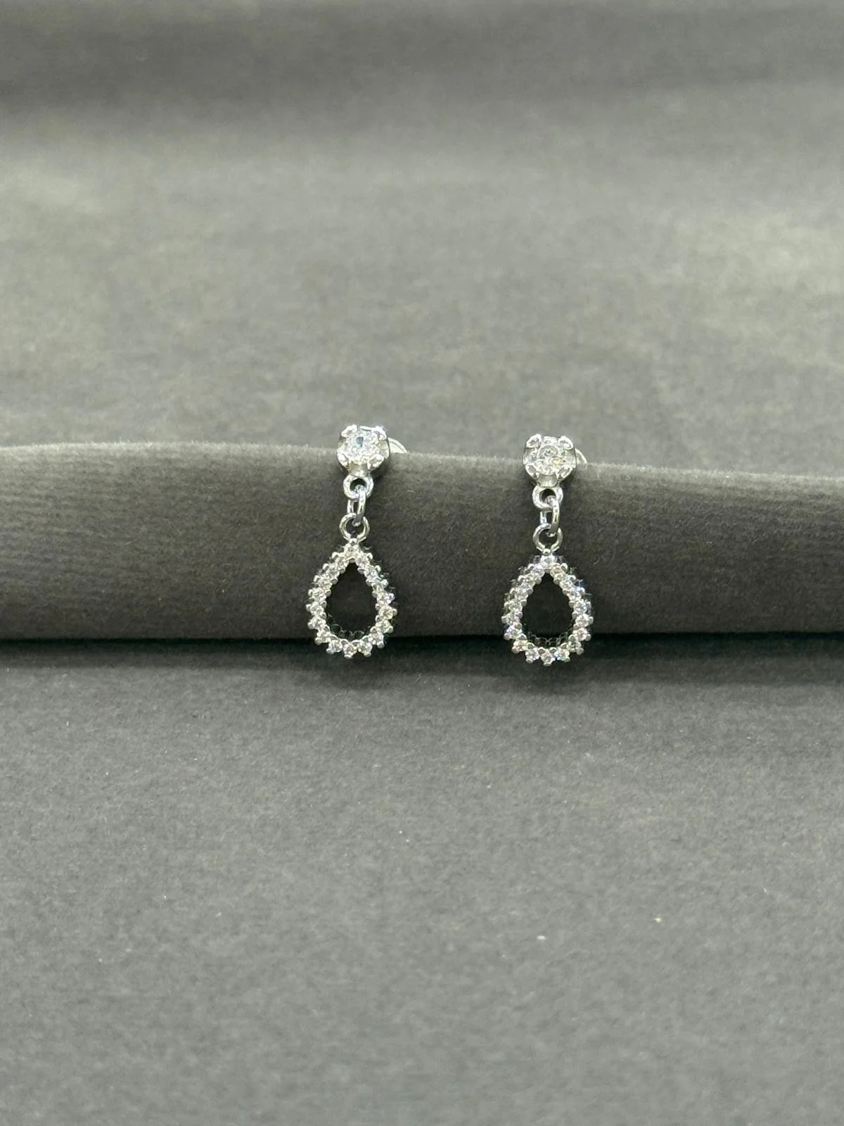 Pair of silver teardrop earrings on a gray surface