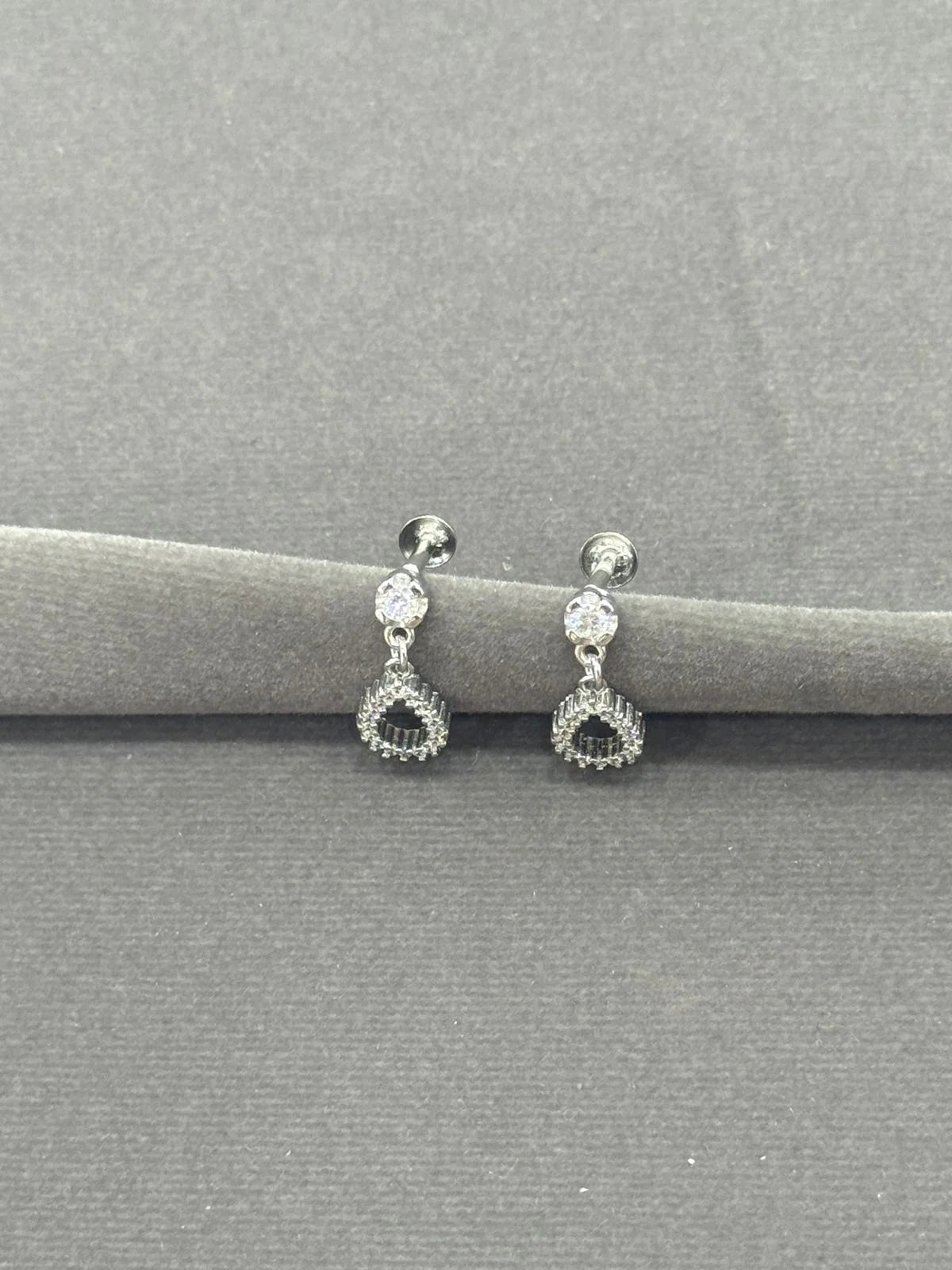 Pair of silver earrings with gemstones on a gray background