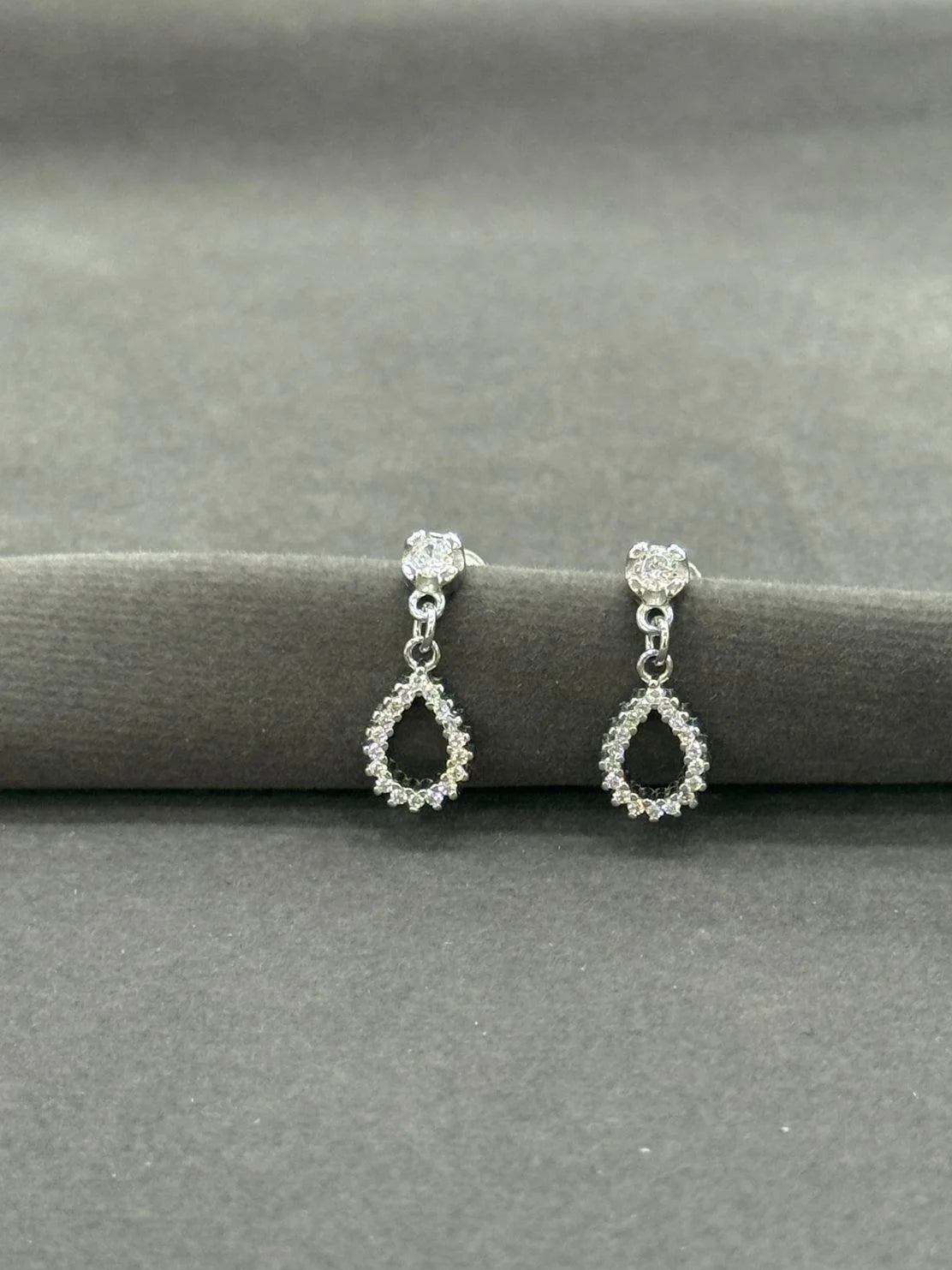 Pair of silver teardrop earrings on a gray surface