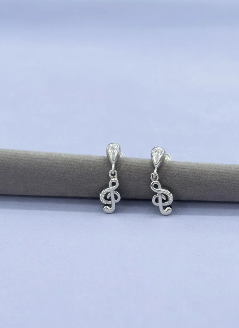 Silver music earrings on a gray surface with a light blue background