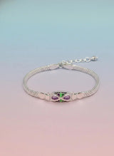 Silver bracelet with a green and purple gemstone on a gradient background