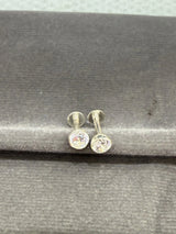 Pair of silver stud earrings with clear gemstones on a gray surface