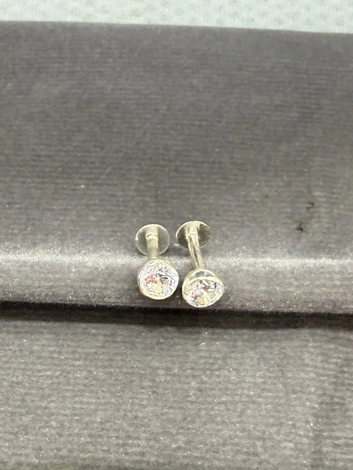 Pair of silver stud earrings with clear gemstones on a gray surface